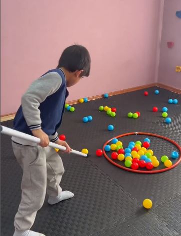 Çemberdeki renkli toplarla hareket çalışması yapan çocuk