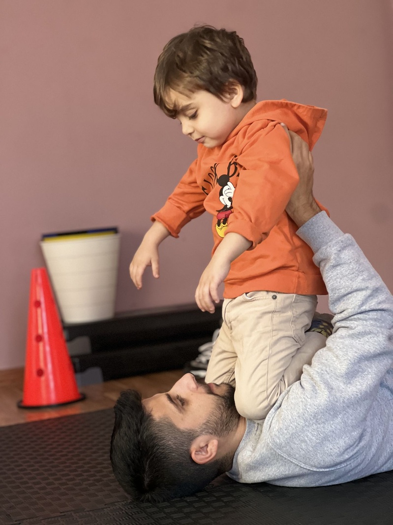 Eğitmenle yerde hareket oyunu oynayan çocuk