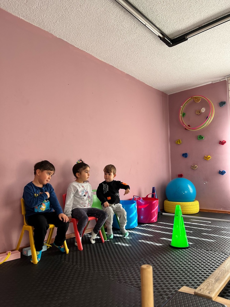 Hareket etkinliği öncesinde yan yana oturan çocuklar