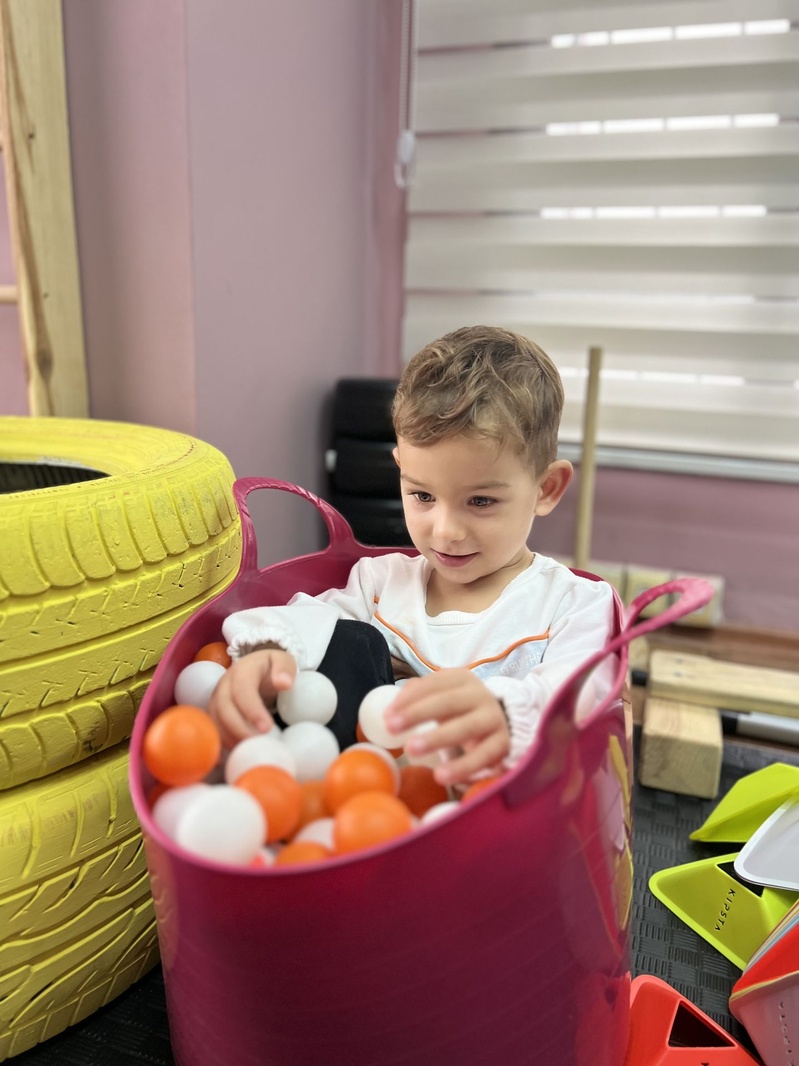 Renkli topları sepetten alan çocuk