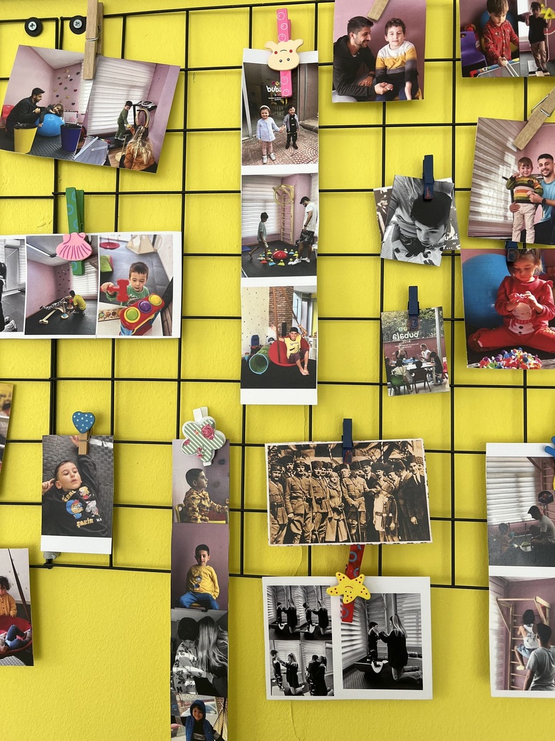 Merkezin sarı duvarındaki eğitim fotoğrafları panosu