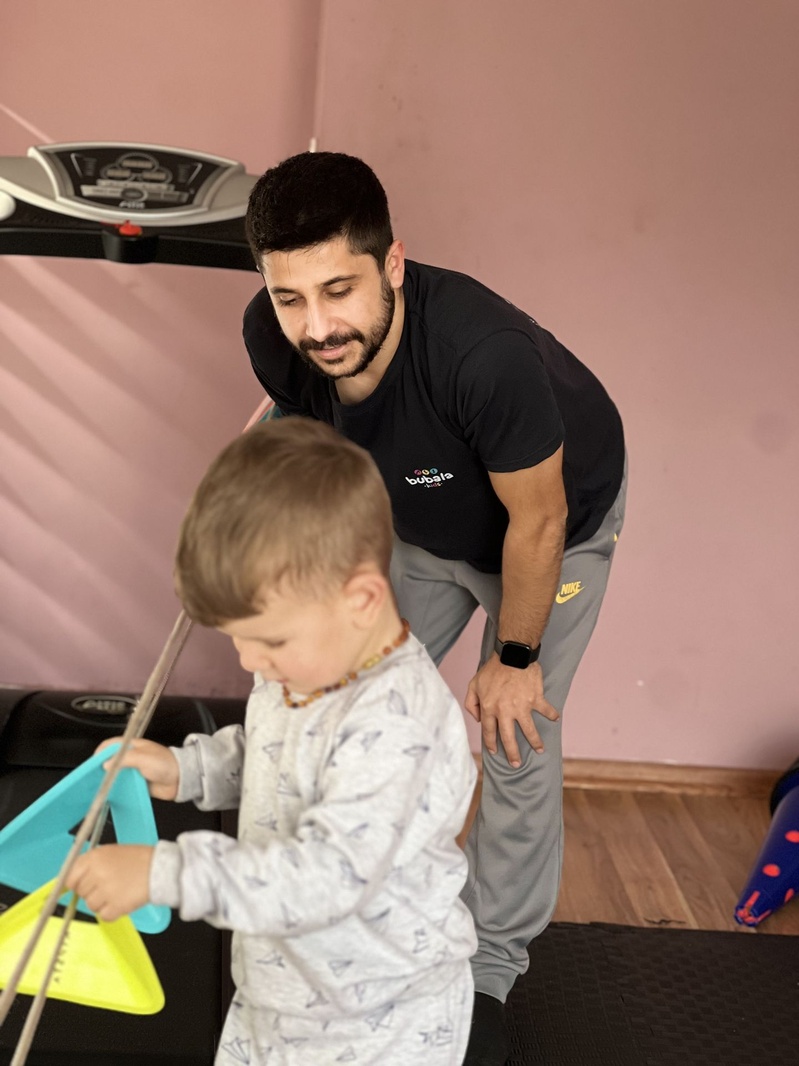 Eğitmen eşliğinde hareket materyalleriyle çalışan çocuk